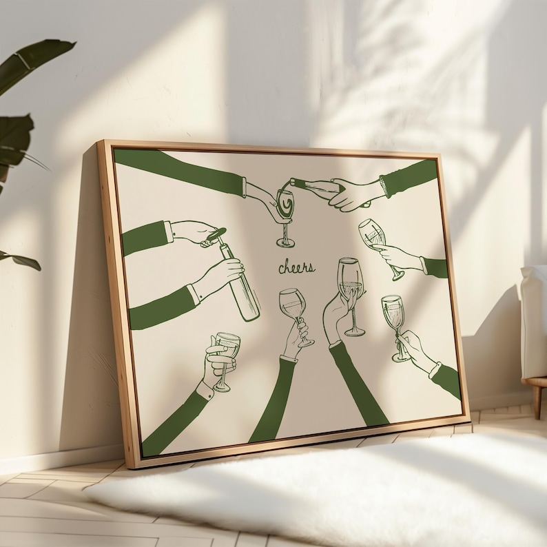 May include: A framed art print featuring a green line drawing of hands toasting with wine glasses. The word "cheers" is written in a script font. The artwork is set against a cream-colored background and framed in a light wood.