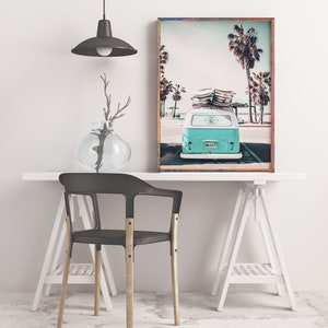 May include: A teal blue vintage van with surfboards on the roof parked in front of palm trees. The van has a license plate that reads "SURF 67". The image is framed in a wooden frame.