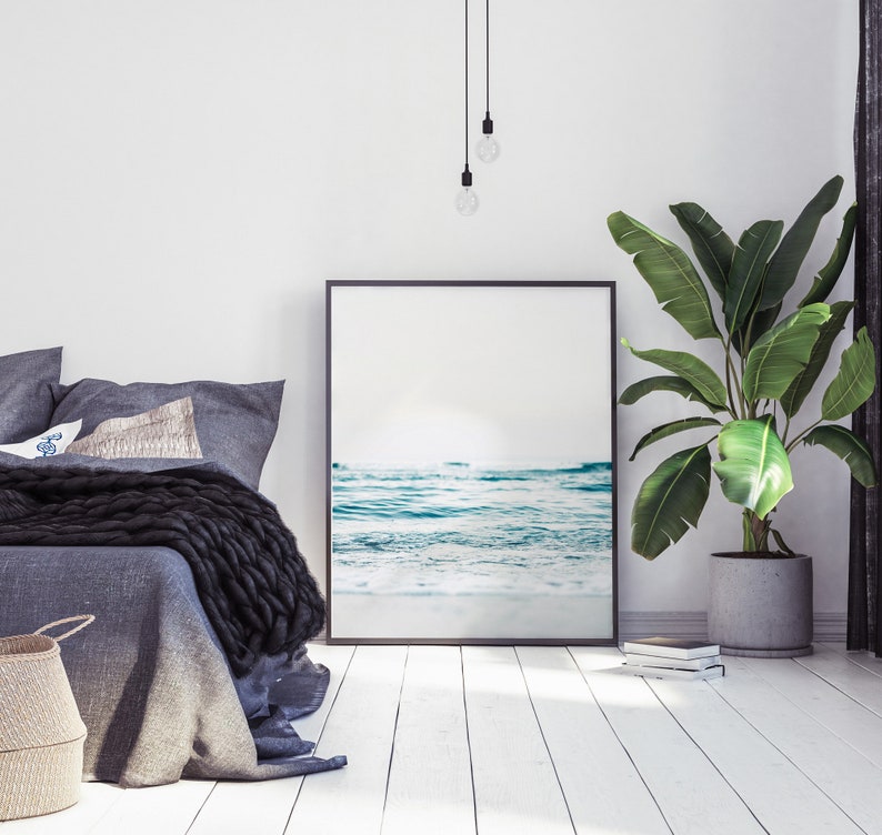 Peut inclure: Int&eacute;rieur d'une chambre &agrave; coucher avec un lit, une photo encadr&eacute;e en noir d'une sc&egrave;ne de plage, une plante en pot et un luminaire suspendu.