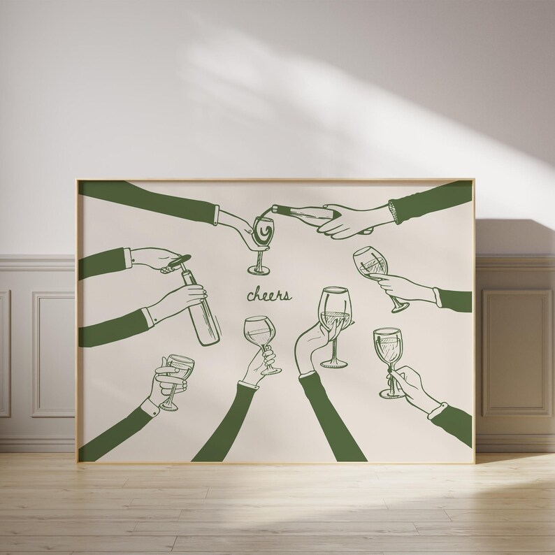 May include: A framed print featuring a green line drawing of hands toasting with wine glasses and bottles. The word "cheers" is written in cursive. The artwork is set against a cream-colored background.