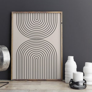 May include: A framed print with a minimalist geometric design featuring black arches on a beige background. The print is displayed on a wooden surface with white vases and candles.
