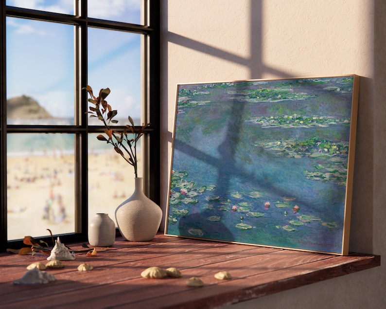 May include: A framed painting of water lilies in shades of blue and green, with a few pink flowers visible. The painting is hanging on a wall next to a window with a view of a beach.