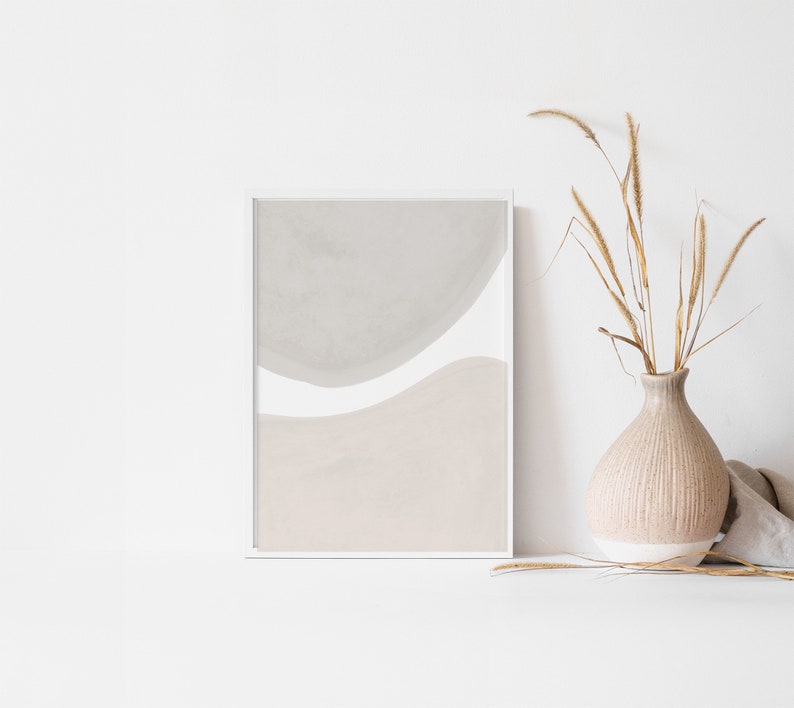May include: A framed abstract print with a white background and two overlapping shapes in shades of grey and beige.