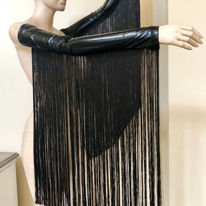 May include: A pair of black long-sleeved gloves with fringe. The gloves are made of a shiny, stretchy material.