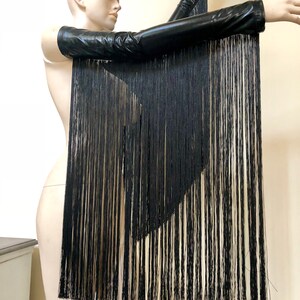 May include: Black leather arm warmers with long black fringe hanging from the bottom. The fringe is layered and creates a dramatic look.