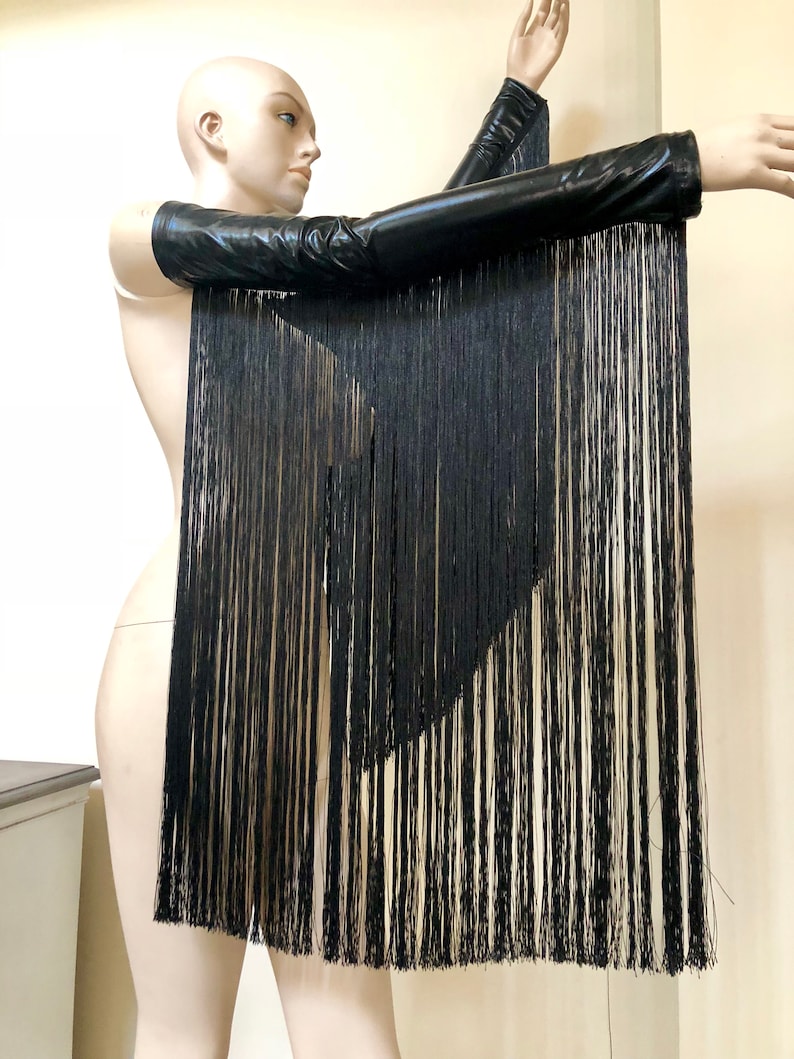 May include: Black leather arm warmers with long black fringe hanging from the bottom. The fringe is layered and creates a dramatic look.