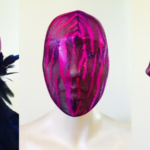 May include: A pink and black patterned face mask made of sheer fabric. The mask covers the entire head and has a tie at the back.