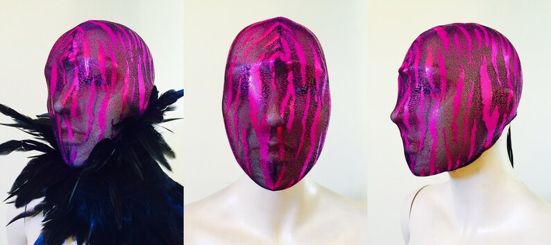 May include: A pink and black patterned face mask made of sheer fabric. The mask covers the entire head and has a tie at the back.