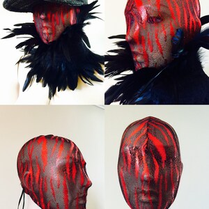 May include: A red and black patterned mesh mask covers a mannequin's head. The mask has a tie at the back of the neck. The mask is shown from the front, side, and back.