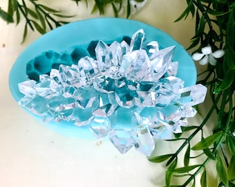 May include: A turquoise silicone mold shaped like a cluster of clear quartz crystals.