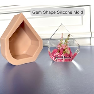 Peut inclure: Un moule en silicone rose en forme de pierre précieuse, avec un moulage en résine transparente de la même forme rempli de fleurs roses. Le moule est destiné à la fabrication et à la création de bijoux en résine ou de décoration pour la maison.