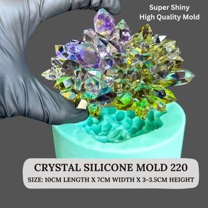 Puede incluir: Un molde de silicona turquesa para racimos de cristales. El molde contiene una réplica detallada de una formación de cristal multicolor. El texto de la imagen dice "Super Shiny High Quality Mold" y "CRYSTAL SILICONE MOLD 220". Tamaño: 10cm largo x 7cm ancho x 3-3.5cm alto.