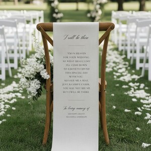May include: A wooden chair with a cream banner inscribed with the words "I will be there", a poem, and names. The scene is set outdoors with white flowers and petals, suggesting a wedding ceremony.