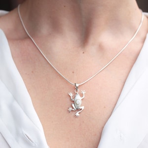 May include: A silver chain necklace with a white shell frog pendant.