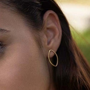 Puede incluir: Primer plano de la cara de una mujer con purpurina en las cejas. Lleva una camisa amarilla y pendientes de oro.