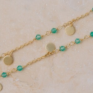 May include: Two gold chains with green gemstone beads and gold disc pendants.
