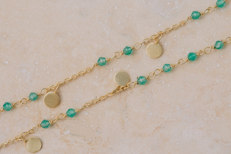 May include: Two gold chains with green gemstone beads and gold disc pendants.