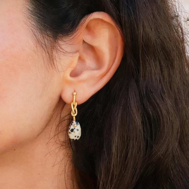 May include: Gold knot dangle earrings with a black and white dalmatian jasper stone.