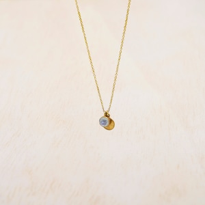 May include: A gold chain necklace with a small, round, white pendant.