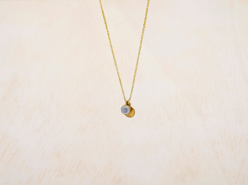 May include: A gold chain necklace with a small, round, white pendant.