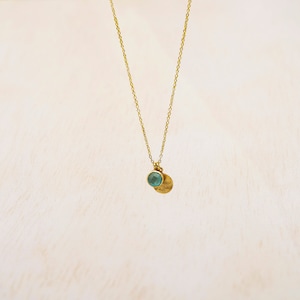 May include: A gold chain necklace with a small, round, teal-colored gemstone pendant and a gold disc charm.