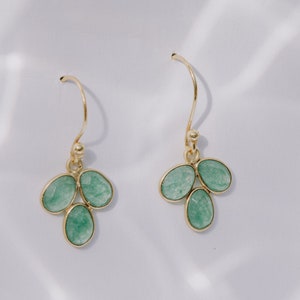 May include: A pair of gold dangle earrings with three green gemstone drops each.