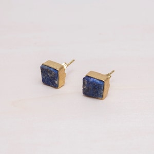 May include: A pair of gold stud earrings with square blue lapis lazuli stones.