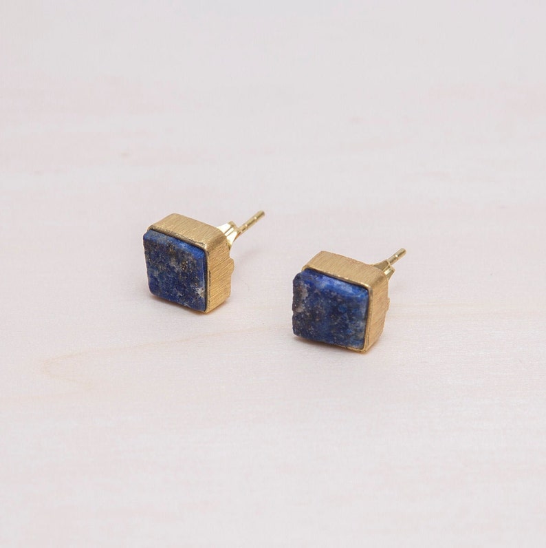 May include: A pair of gold stud earrings with square blue lapis lazuli stones.