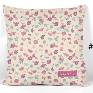 May include: A cream-colored pillow with a pink and blue butterfly and flower pattern. The pillow has the text "Polina Po Prints" in pink.