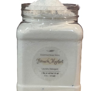 Może przedstawiać: Biały plastikowy słoik wypełniony białym proszkiem do prania. Etykieta zawiera napis "Essential Soap Store French Market Laundry Detergent 2 Tbsp. per each load. HE safe. 32 oz. 60 Loads."
