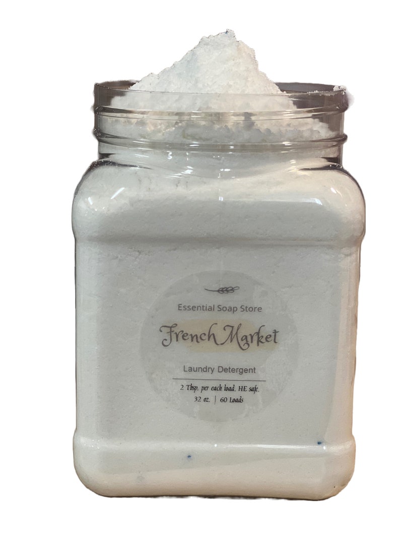 Może przedstawiać: Biały plastikowy słoik wypełniony białym proszkiem do prania. Etykieta zawiera napis "Essential Soap Store French Market Laundry Detergent 2 Tbsp. per each load. HE safe. 32 oz. 60 Loads."