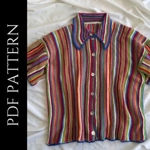 May include: A short-sleeved crochet shirt featuring a vibrant vertical striped pattern in multiple colors including red, blue, green, yellow, and purple. The shirt has a collared neckline, a front button closure with five white buttons, and text reading PDF PATTERN.