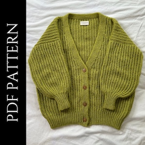 Puede incluir: Un cárdigan de punto verde con cuello en V y cierre de botones. El cárdigan tiene una textura acanalada y mangas largas.