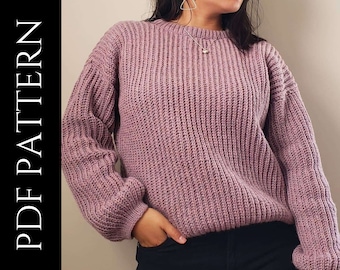 May include: A purple knitted sweater with a round neckline and long sleeves. The sweater has a ribbed texture.