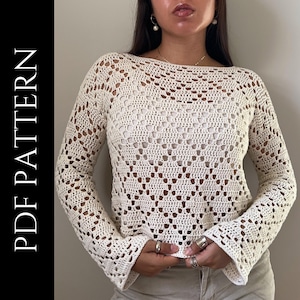 May include: Cream-coloured crochet top with long sleeves and a boat neck. The openwork design reveals a glimpse of the underlayer. The text "PDF PATTERN" is printed vertically on the left side of the image.