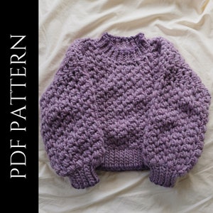 Può includere: Un maglione di lana viola con una trama spessa e un collo rotondo.