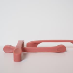 May include: Three pink plastic drawer pulls with a rounded, curved design.