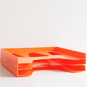 Op de afbeelding: Drie oranje plastic mapbakken gestapeld op elkaar. De bakken hebben een lip aan de voorkant en zijn ontworpen om papier in te bewaren.