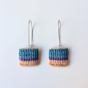 May include: A pair of teal and purple woven earrings with silver hooks.