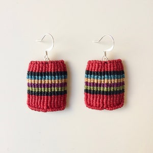May include: A pair of red, black, green and blue striped earrings with silver hooks.