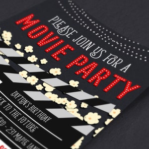 May include: Black and white movie clapperboard with red text that says "MOVIE PARTY" and "PLEASE JOIN US FOR A". The background is black with white popcorn scattered on it. The text also says "TO CELEBRATE" and "PAYTON'S BIRTHDAY".