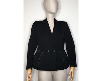 May include: A black double-breasted blazer with a tailored fit, displayed on a mannequin. The blazer features a notched lapel, two rows of buttons, and subtle silver stitching along the seams. The jacket has a structured silhouette.