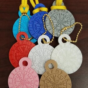 May include: Set of six colorful round pendants with a compass design and runes around the edge. The pendants are made of plastic and have a gold chain attached.