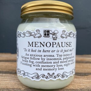 May include: A glass jar with a gold lid and a white label that reads "MENOPAUSE" and "Is it hot in here or is it just me?"  The label also includes a list of symptoms associated with menopause, including fatigue, insomnia, palpitations, brain fog, confusion, mood swings, memory loss, and night sweats.