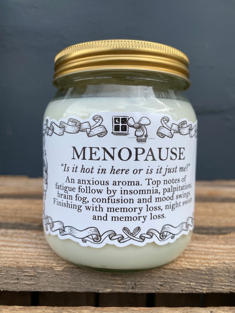 May include: A glass jar with a gold lid and a white label that reads "MENOPAUSE" and "Is it hot in here or is it just me?"  The label also includes a list of symptoms associated with menopause, including fatigue, insomnia, palpitations, brain fog, confusion, mood swings, memory loss, and night sweats.