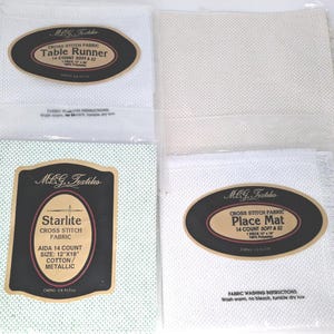 Peut inclure: Quatre paquets de tissu pour point de croix MCG Textiles comprenant un chemin de table blanc, un morceau de tissu beige, un tissu Aida 14 count vert clair Starlite et un set de table blanc. Chaque emballage porte une étiquette avec les détails.