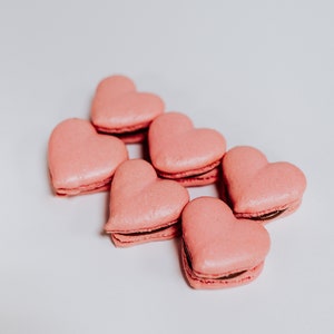 May include: Six pink heart-shaped macarons with chocolate filling.
