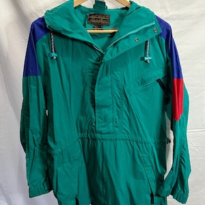 Könnte beinhalten: Eine grüne, blaue und rote Kapuzenjacke mit Reißverschluss und Kordelzug an der Taille. Die Jacke hat ein Etikett mit der Aufschrift "Eddie Bauer" und "Mountain Gear".