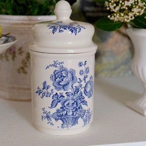 Peut inclure: Pot en céramique blanche avec un motif floral bleu. Le pot a un couvercle et est décoré de fleurs et de feuilles bleues.