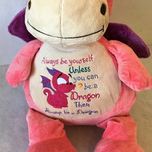 Puede incluir: Juguete de peluche de dragón rosa y morado con texto bordado que dice "Siempre sé tú mismo A menos que puedas ser un Dragón Entonces Siempre sé un Dragón".